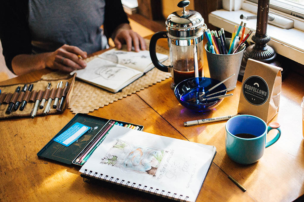 A man working on art with different tools on the table