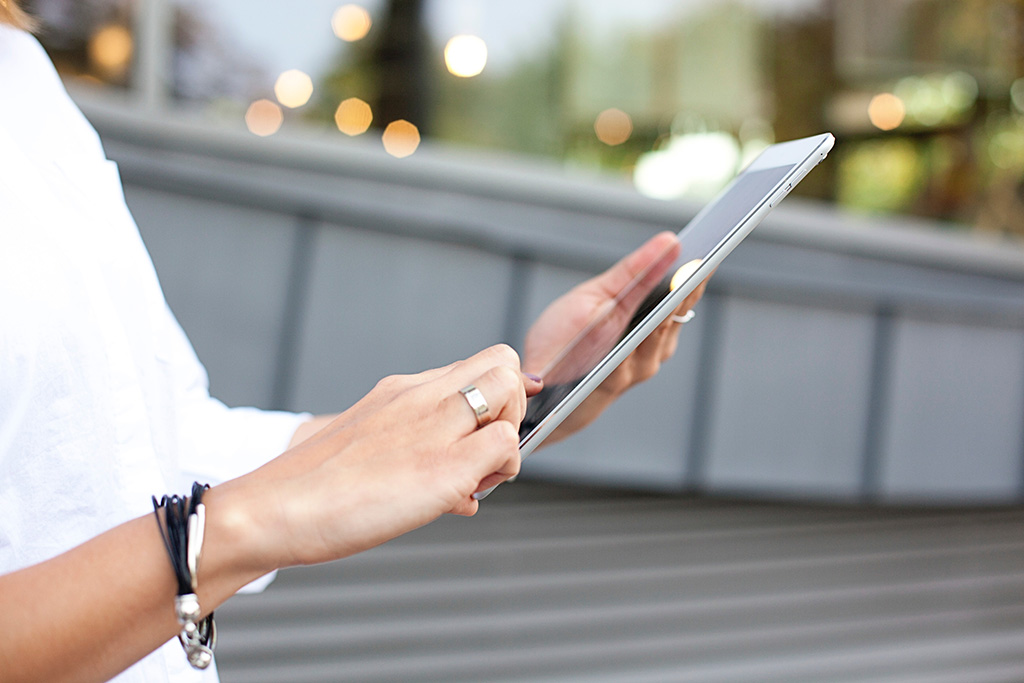 A person drafting an email on their tablet while on the street