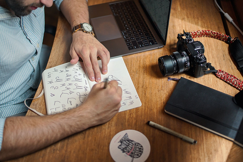 A man's hand while drawing something on a piece of paper.