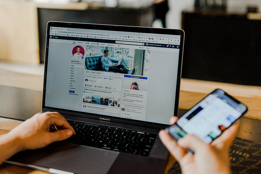 A person using a social media platform in a laptop while using another application in a smartphone